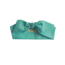 Load image into Gallery viewer, Teal headband with a brand label on a white background
