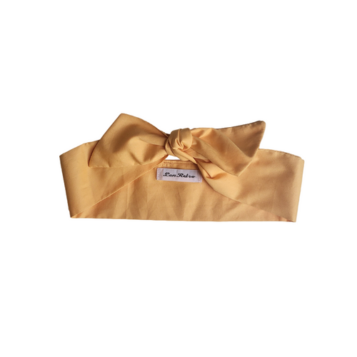 A golden yellow cotton hair scarf tied in a knot on a white background.