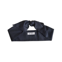 Load image into Gallery viewer, Black headband with a brand label on a white background