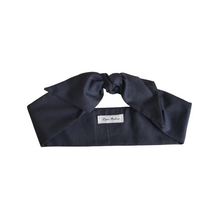Load image into Gallery viewer, A folded black cotton hair scarf with a brand tag visible, displayed against a white background.