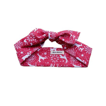Load image into Gallery viewer, A red and white reindeer print hair scarf laid flat on a surface.