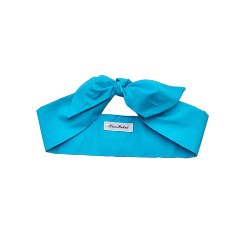 A turquoise cotton headscarf displayed on a flat surface with a brand tag visible.