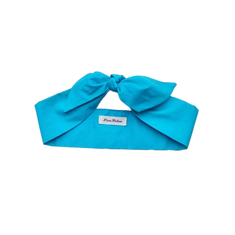 A turquoise cotton headscarf displayed on a flat surface with a brand tag visible.