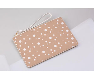 blush and white dotty print clutch bag on a light grey background