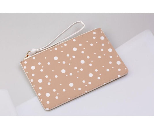 blush and white dotty print clutch bag on a light grey background