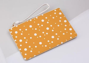  mustard and white dotty clutch bag on a light grey background