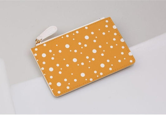 mustard and white dotty coin purse on a light grey background